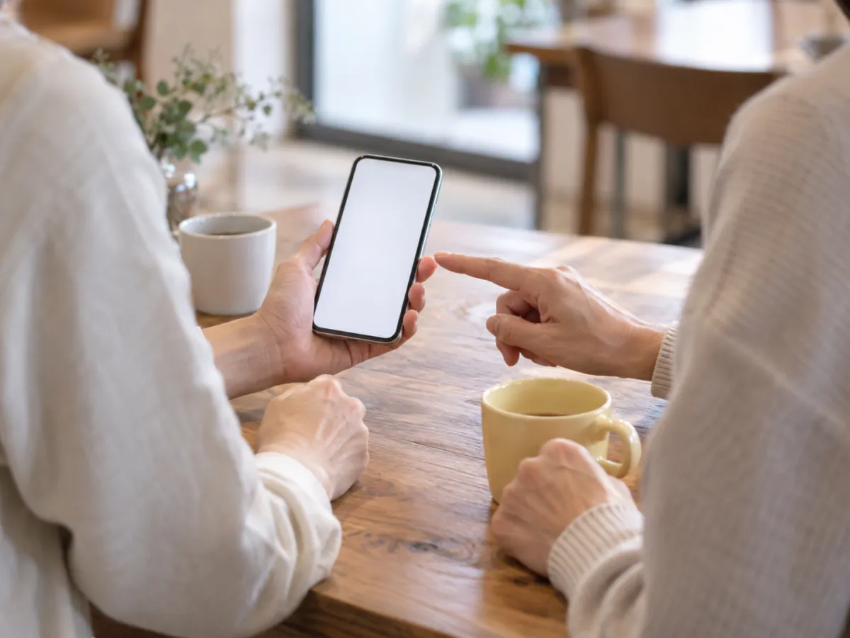 カフェで、スマホの画面を見せて教えている手元